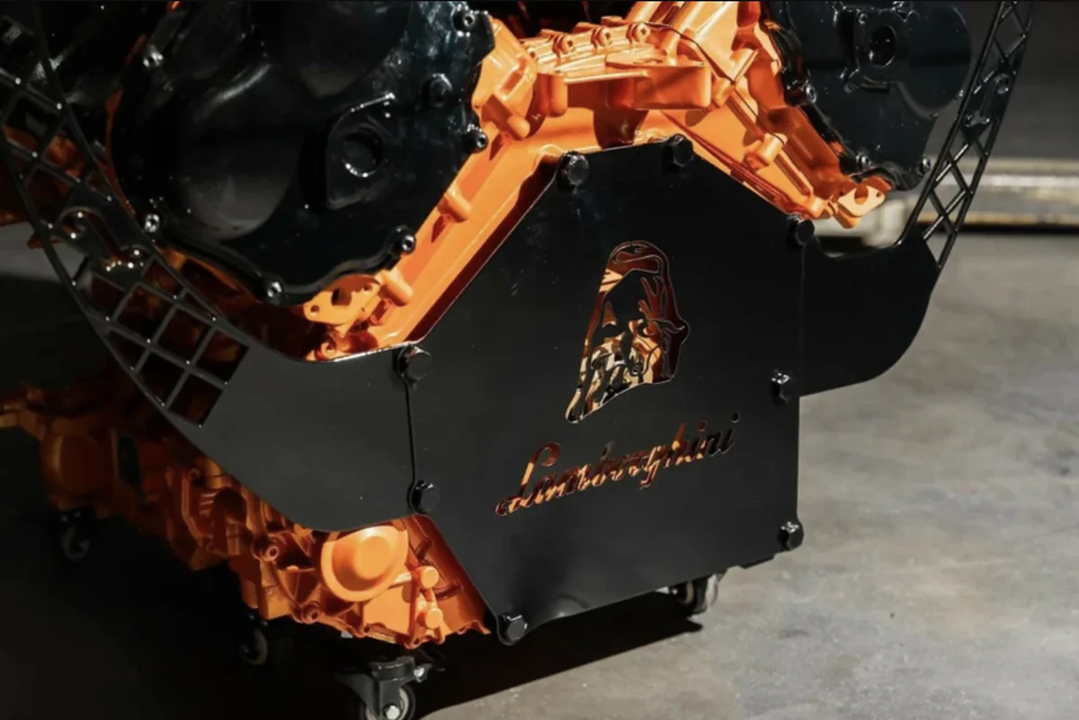 Bouclier Lamborghini sur le panneau noir devant le bloc moteur orange